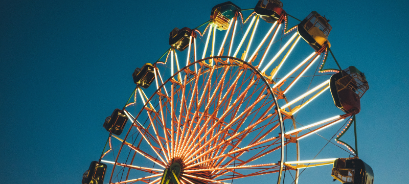The top half of a ferris wheel is pictured against an almost-evening dusk sky